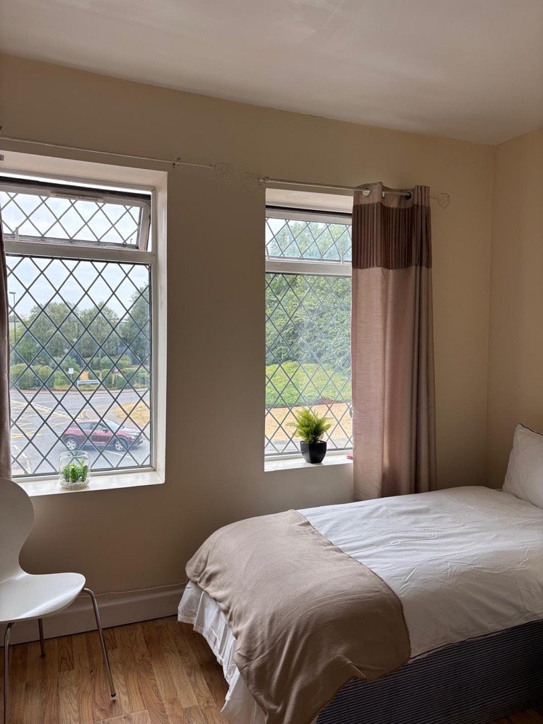 A bright bedroom with two windows looking out over trees